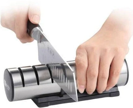 Une femme utilise l’aiguiseur de couteau professionnel, pour aiguiser un couperet