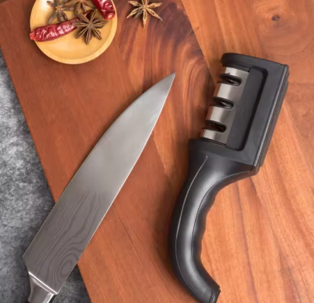 Image de l'aiguiseur couteau sur une planche à découper en bois, près d'un couteau du chef bien aiguisé