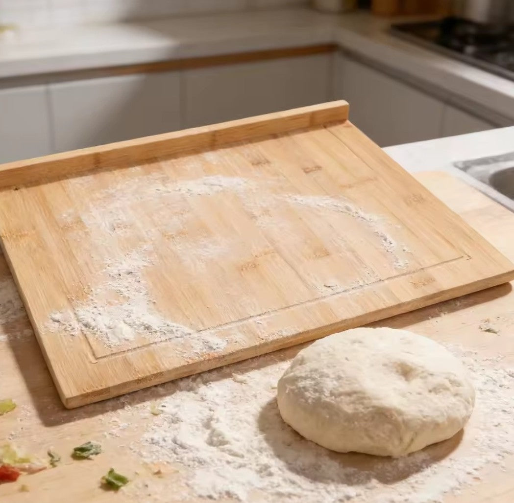 Grande planche à découper en bois avec rebord utilisée pour pétrir une pâte à pain sur un plan de travail fariné.