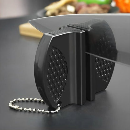 Mini aiguiseur couteau noir de forme plutôt ronde avec une fente en V dessous et dessus.