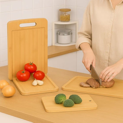 Planche à découper BambouCut, montrant les trois tailles mais avec une femme qui coupe un aliment au couperet