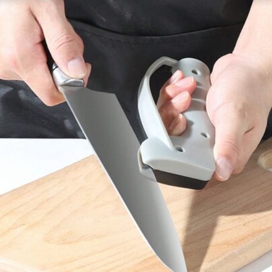 Un homme est en train d'aiguiser un couteau du chef avec une bonne prise en main de son aiguiseur couteau