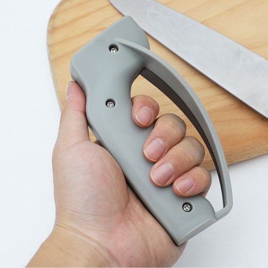 Une main gauche masculine tient l'aiguiseur couteau professionnel en montrant le côté gris