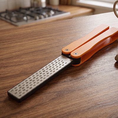 image de l'aiguiseur de couteau pliable orange sur une table en bois