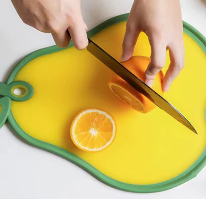 Une jeune femme tranche une orange sur sa planche à découper en forme de poire