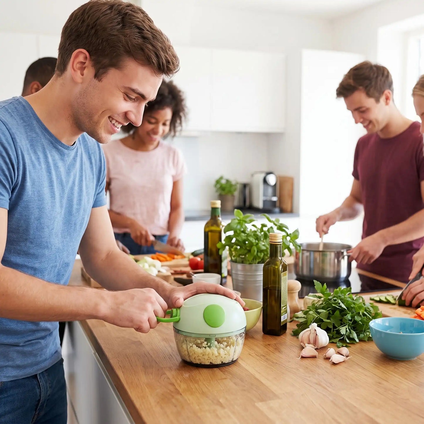 Un étudiant dans une cuisine collective, est en train de hacher de l'ail dans son mini hachoir vert. 