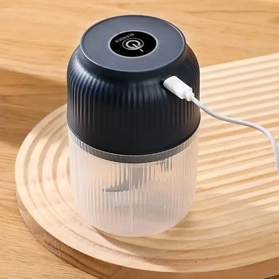 Le hachoir électrique en train de se faire charger avec son fil USB, sur une jolie planche à découper en bois