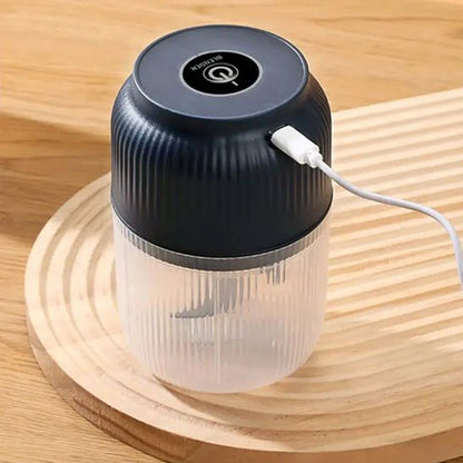 Le hachoir électrique en train de se faire charger avec son fil USB, sur une jolie planche à découper en bois