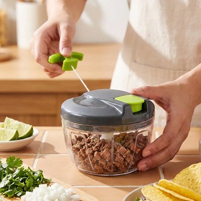Un jeune homme utilise le hachoir manuel gris, clair et transparent pour hacher des cubes de bœuf cuits