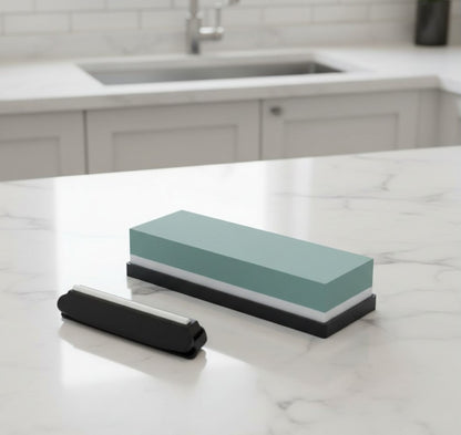 La pierre à aiguiser double face #600 et #1500 avec son ajusteur d'angles et sa base en silicone posés sur un beau comptoir en marbre dans une cuisine de luxe
