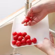 Planche à découper CocktailPro démontrant la facilité de laver des tomates cerises grâce aux petits trous en coin, servant d'égouttoir.
