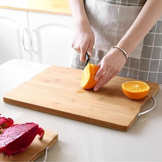 Planche à découper DécoCut en bambou montrant une femme qui tranche une orange fraîche