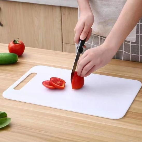 Planche à découper DayliCut blanche, démontrant un jeune qui tranche une tomate