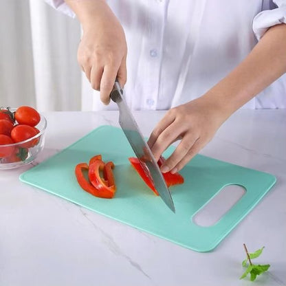 Planche à découper DayliCut de couleur turquoise montrant un cuistot qui coupe des lamelles de poivron rouge