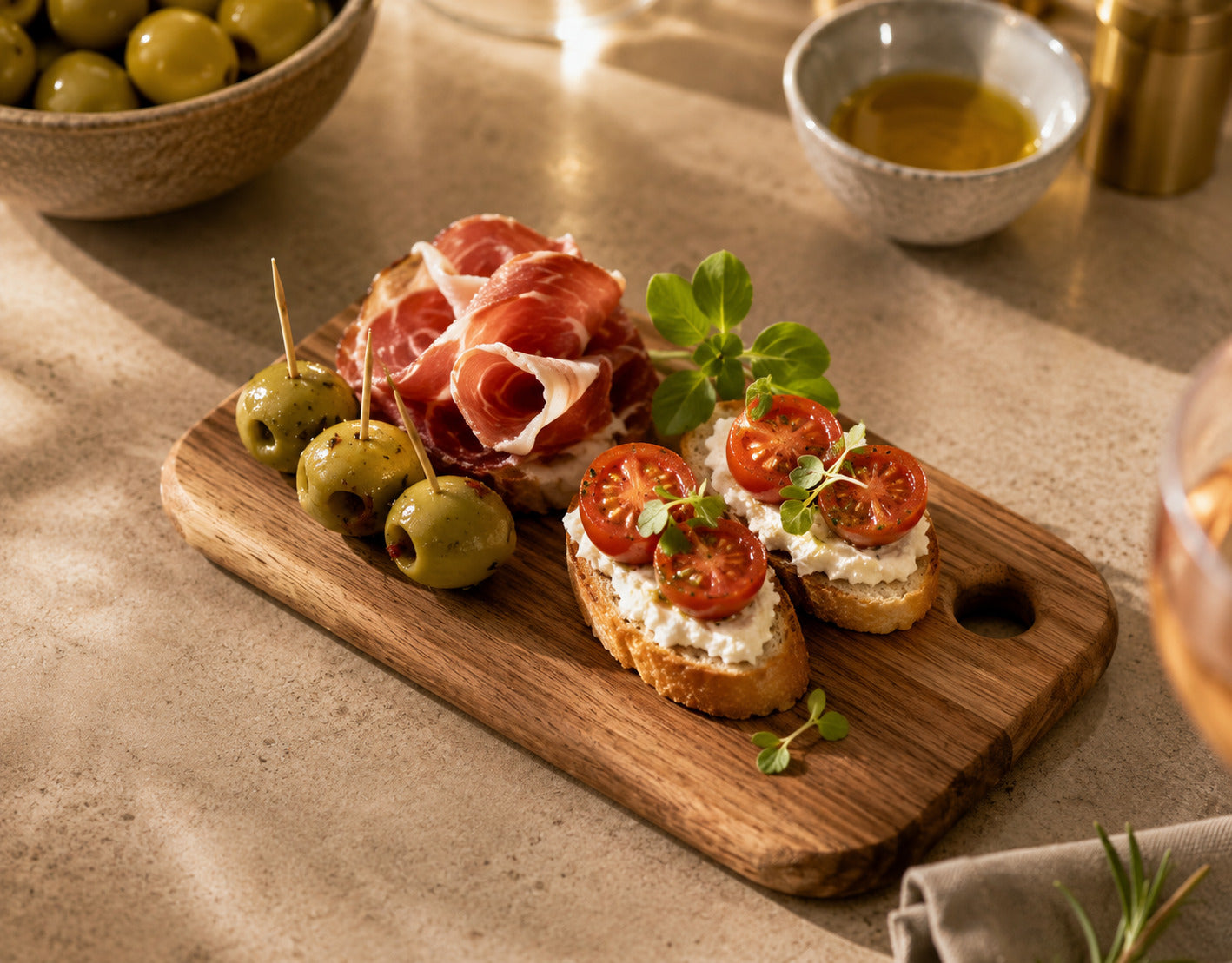 Petite planche en bois d'acacia garnie de tapas, bruschettas, olives et jambon cru, idéale pour l'apéritif.