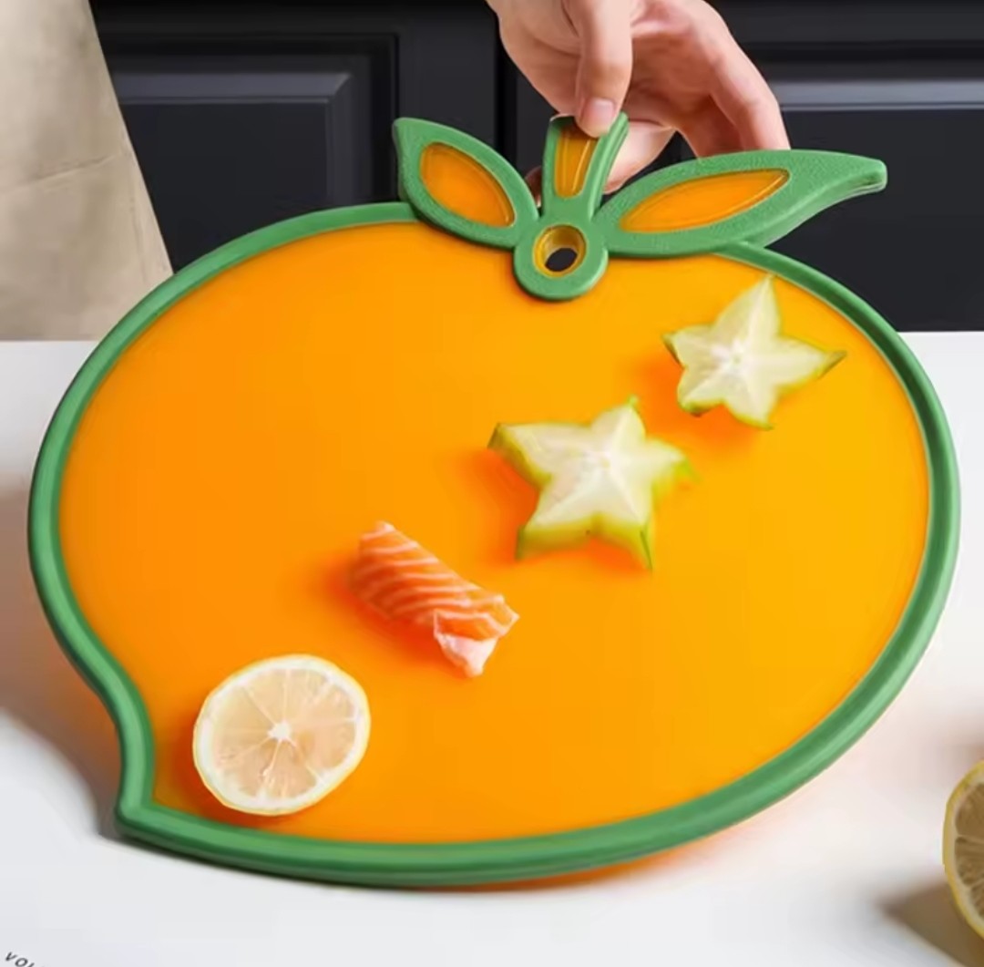 Présentation de la planche à découper en forme de pêche sur laquelle il y a des fruits et un morceau de poisson