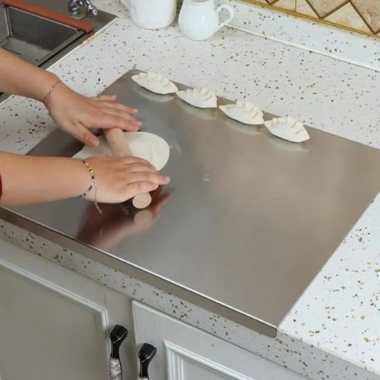 Planche à découper professionnelle en acier inoxydable montrant une femme qui roule facilement de la pâte à dumplings