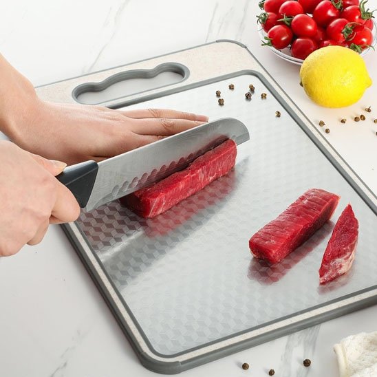 Planche à decouper côté inox sur laquelle une femme y tranche un morceau de boeuf
