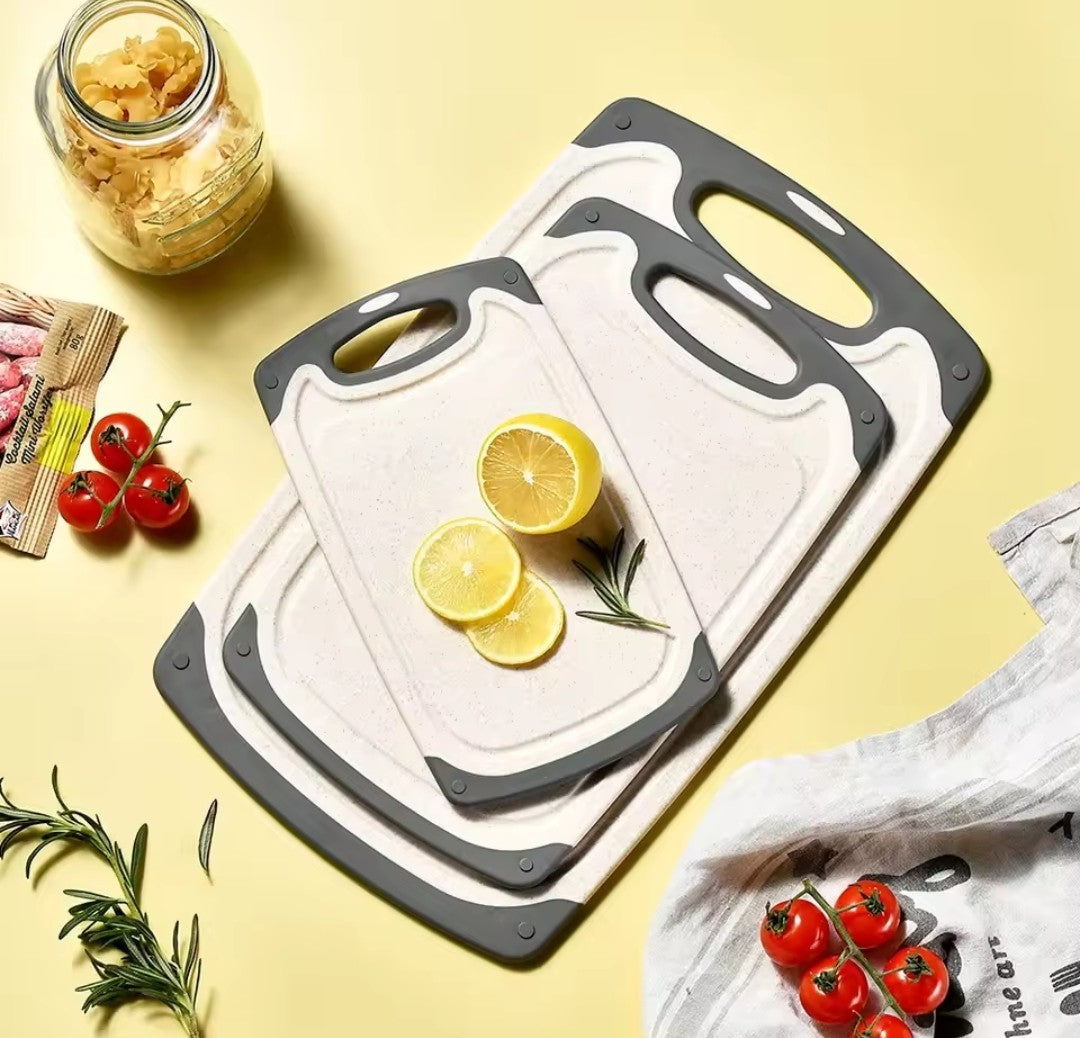 Présentation du trio de la planches à découper en paille de blé joliment disposés sur fond jaune, vue de haut, avec des aliments décoratif qui laissent supposer ne préparation de pâtes en sauce tomate et romarin