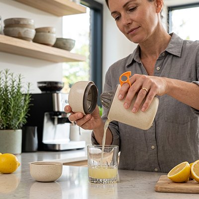 Une femme verse du jus de citron qu'elle vient juste d'extraire avec son presse agrume couleur crème